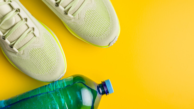 Turnschuhe und eine Trinkflasche vor gelbem Hintergrund