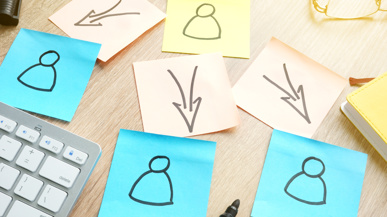 Post-its mit Pfeilen und Menschen (Symbolbild für Auslagerung)