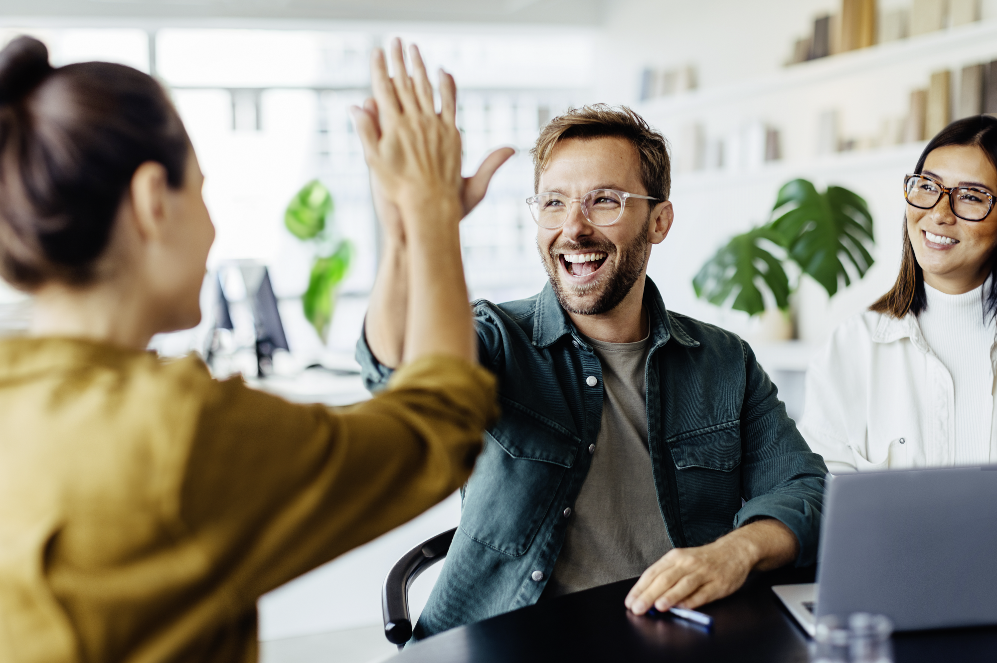 Drei glückliche Menschen, von denen sich zwei ein highfive geben
