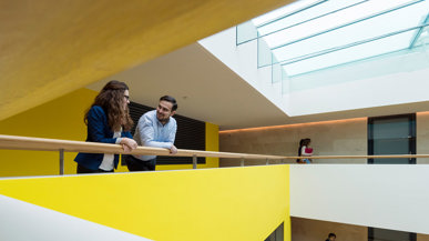 Zwei Personen am Geländer in einem Gebäude