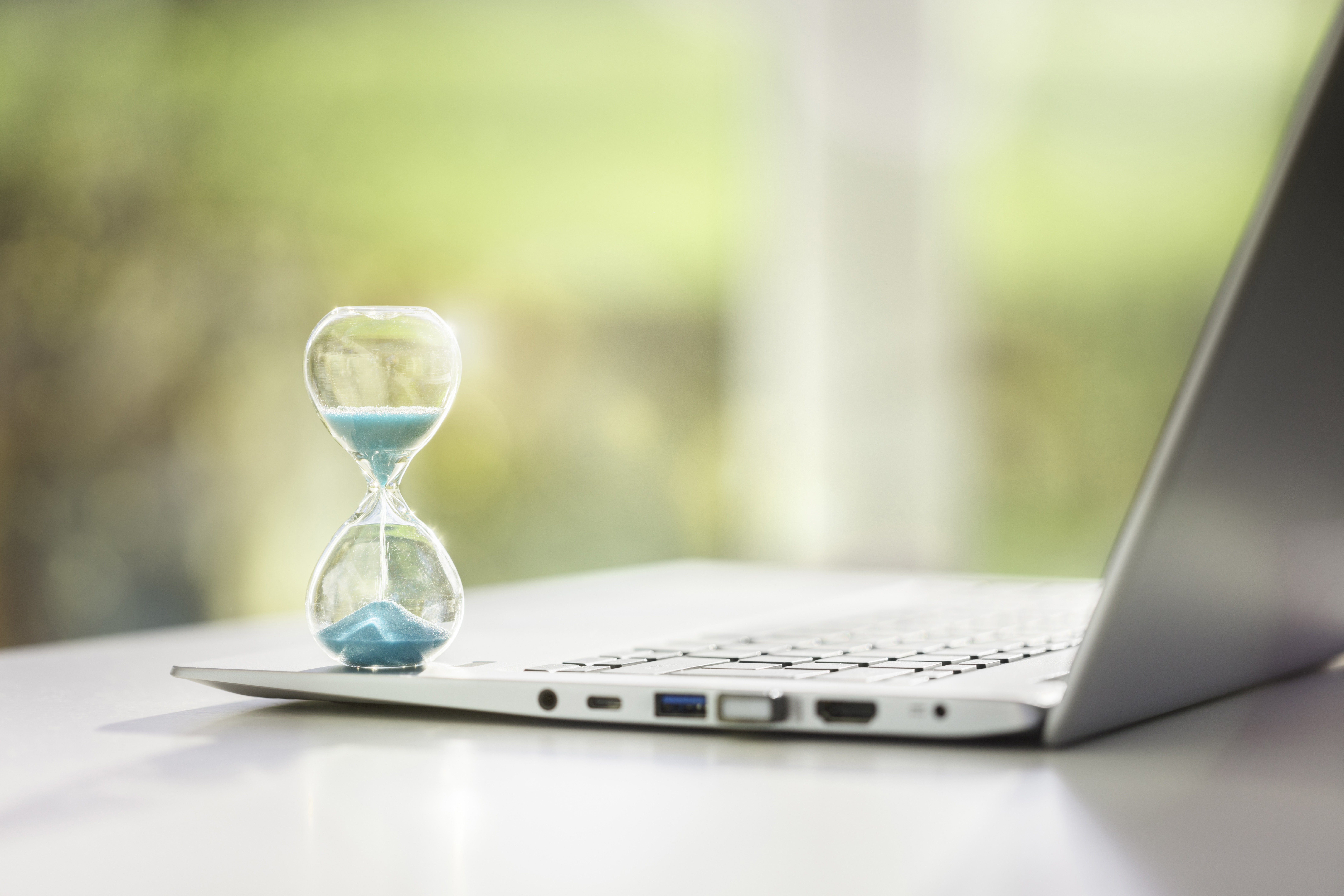 Laptop mit Sanduhr als Symbol der Arbeitszeit