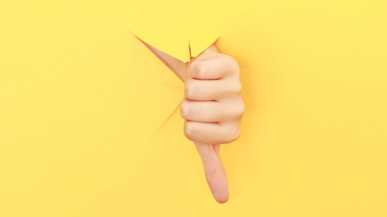 Ein Daumen nach unten vor gelbem Hintergrund als Symbol der Kritik an den Entlassungen der Post