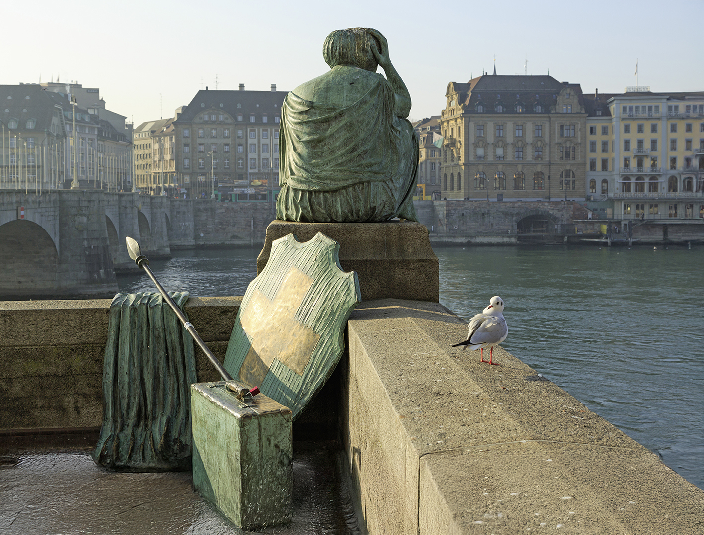 Nachdenkliche Helvetia-Statue mit abgelegtem Schild und Speer mit Blick auf den Rhein in Kleinbasel