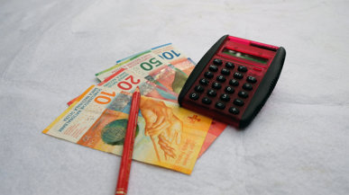 Schweizer Franken Banknoten und ein Rechner, die die finanzielle Thematik der Pressemitteilung über die Lohnoptimierung des Bundes illustrieren.