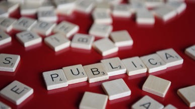 Weisse Scrabble-Bausteine «PUBLICA» auf rotem Grund