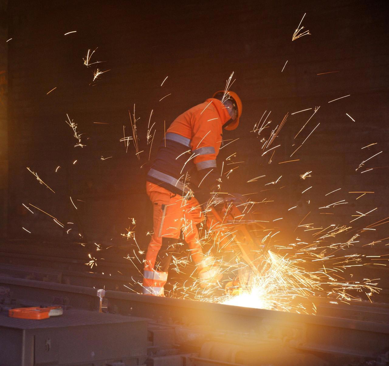 Ein SBB-Mitarbeiter in oranger Arbeitskleidung am schweissen