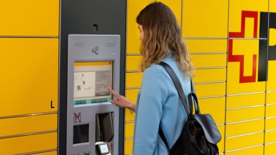 Eine Frau gibt an einem Paketautomaten ein Paket ab