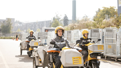 Post-Mitarbeitende auf Motorfahrrädern liefern Post aus