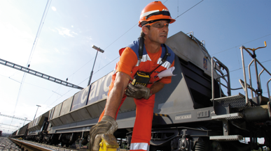Ein Mitarbeitender von SBB Cargo und im Hintergrund ein Güterwagen.
