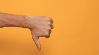 Daumen runter vor gelbem Hintergrund