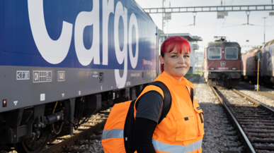 Mitarbeiterin von SBB Cargo steht vor einem Cargo-Wagon