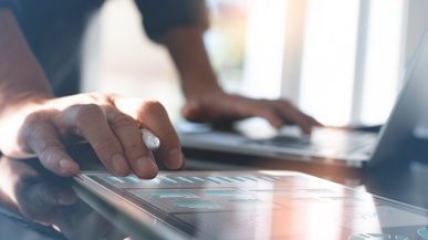 Ein Mann, der am Tisch steht und am PC arbeitet