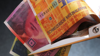 Eine Schere setzt an Schweizer Banknoten an